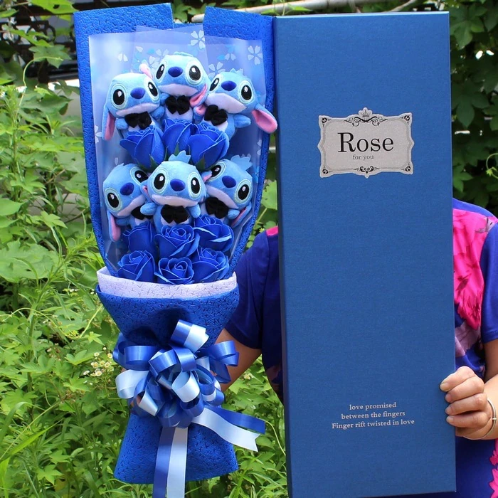 Boeket bloemen met pluche blauwe heer Stitch voor een boom