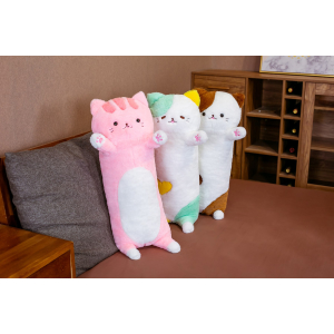 Op een grijze sofa in een kleine woonkamer met een bruine vloer, 3 pluche kussens met de beeltenis van een grote kat op de sofa, één is roze, de tweede is groen en de derde is bruin