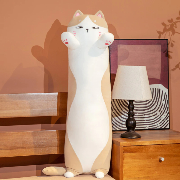 Op een bed met een nachtkastje ernaast, met een wit bedlampje en een frame erachter, ligt een wit met bruin kattenkussen, staand op zijn kleine achterpootjes